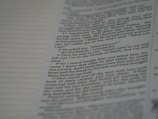 A close-up view of a page from a book, featuring text in a serif font. The text appears to be a narrative or dialogue, with numbered lines and a clear structure. The background is a pale color, likely the paper of the book.