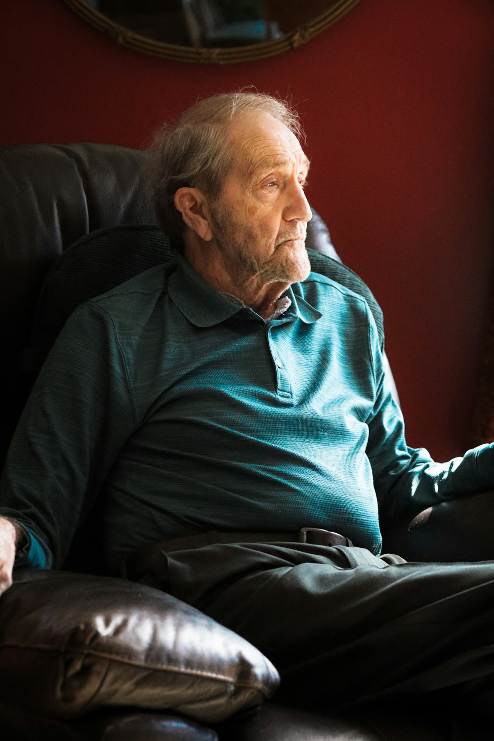 man in green sweater sitting on black sofa