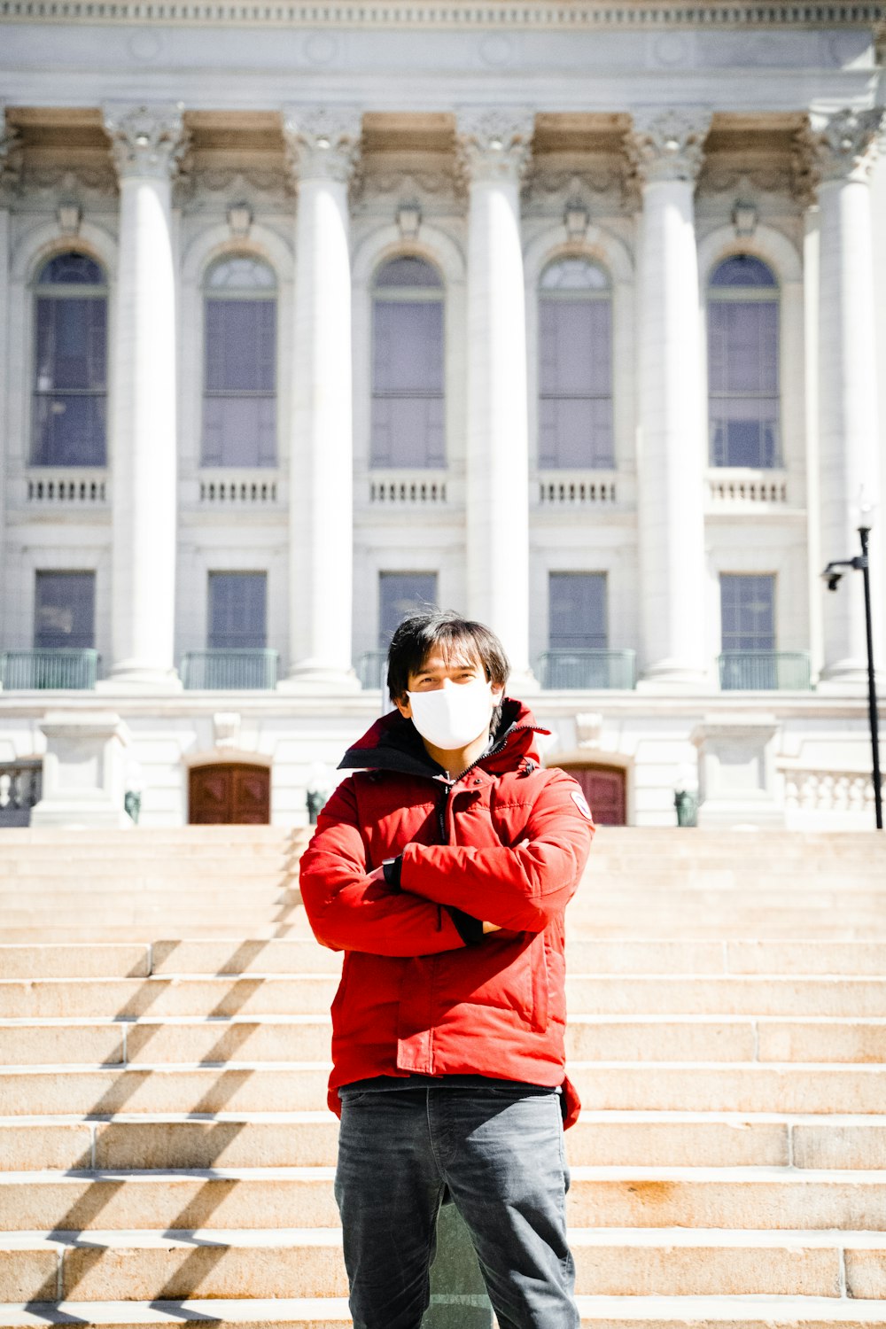 woman in red jacket and black sunglasses standing on white concrete stairs