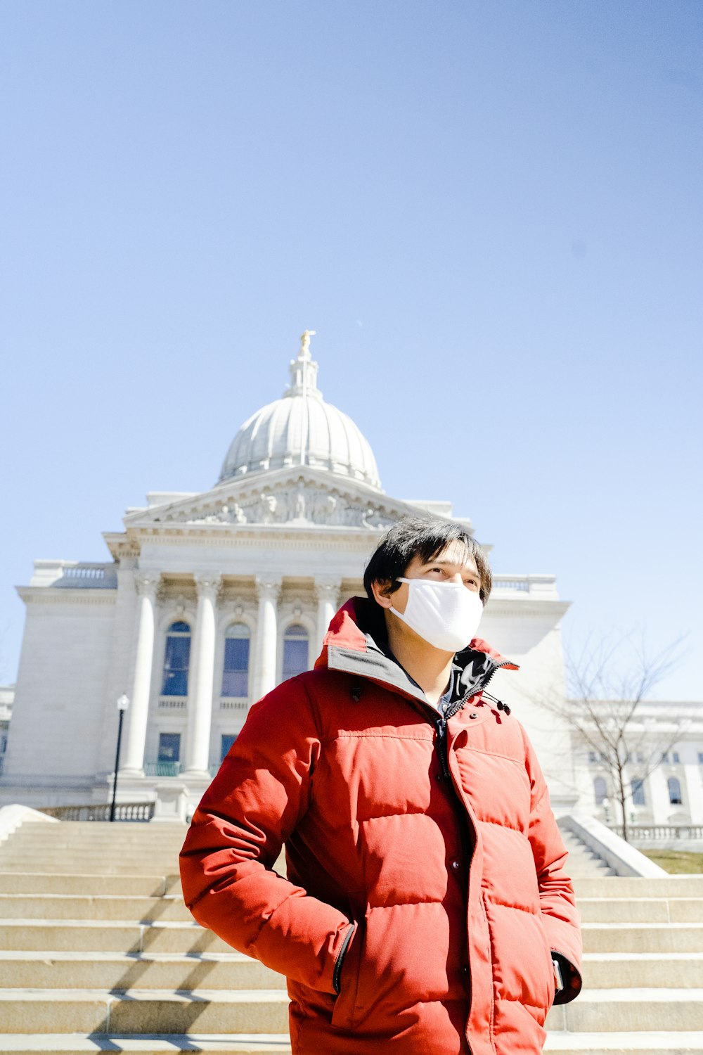 woman in red jacket standing near white building during daytime