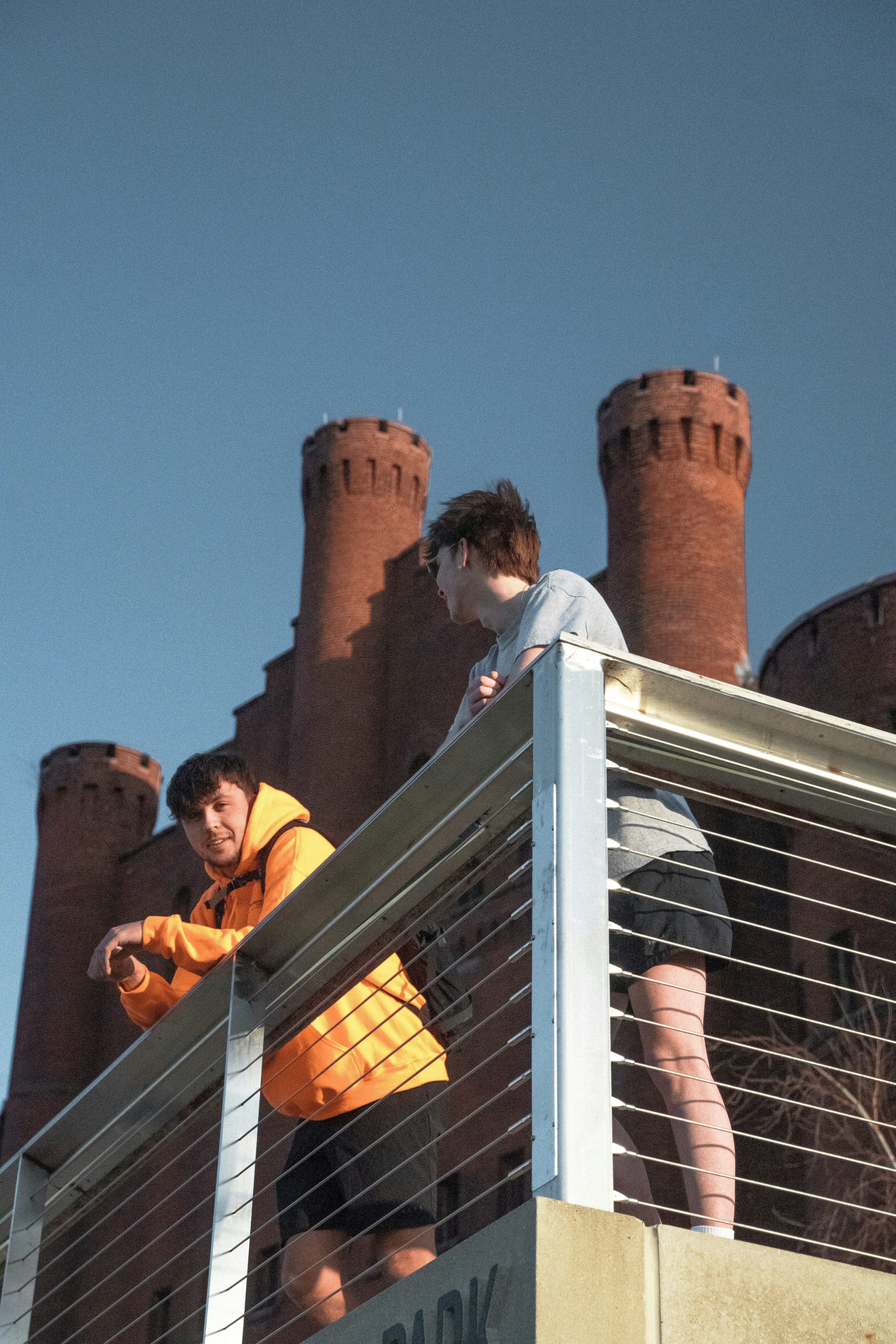 Two men leaning against railing in Madison, Wisconsin with college building in background.