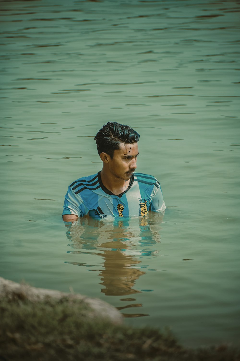 ragazzo in camicia girocollo blu e arancione sull'acqua durante il giorno