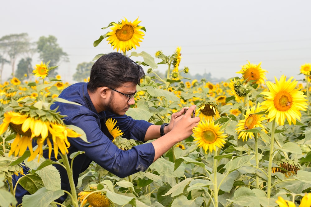 man in blue hoodie holding sunflower during daytime
