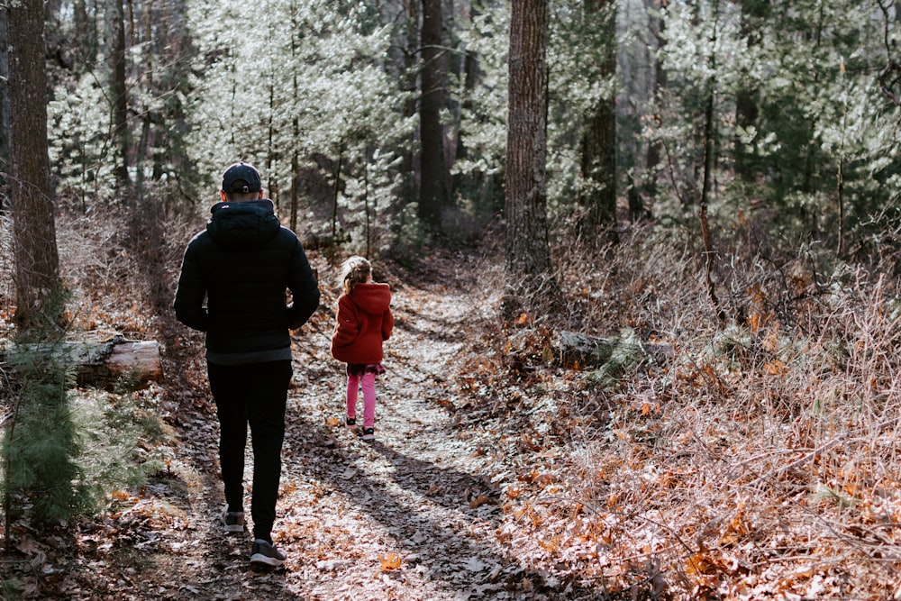 man in black jacket and black pants standing in the middle of forest during daytime