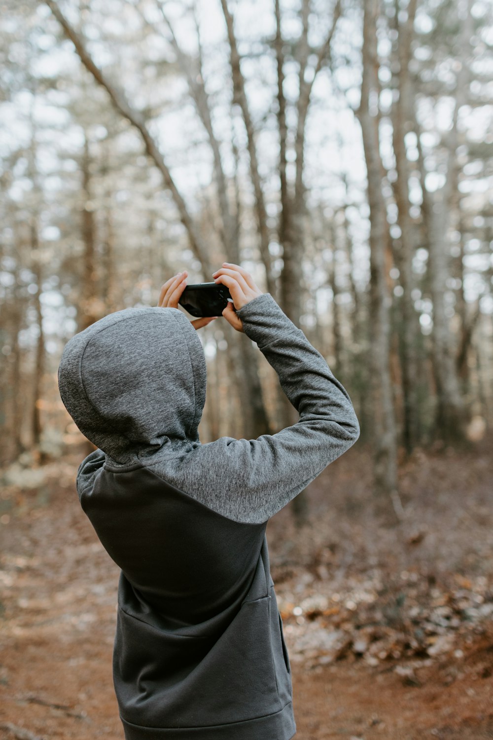 man in gray sweater holding black camera