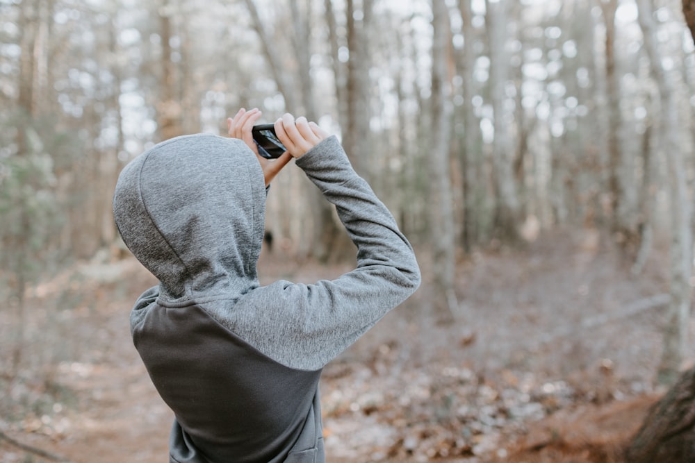 uomo in maglione grigio che tiene la macchina fotografica nera