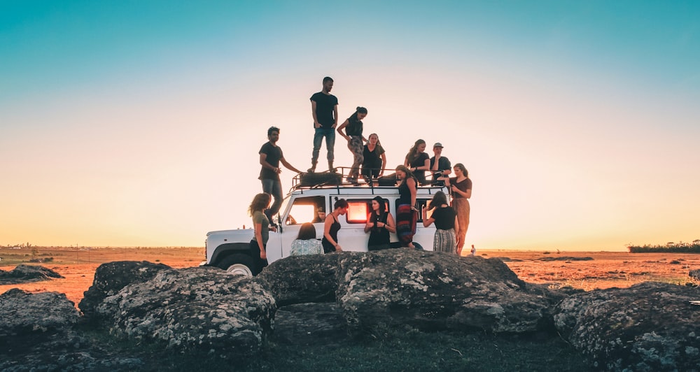 group of people sitting on white car during daytime