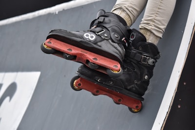 A pair of sturdy wrist guards lying on a bench next to a pair of rollerblades.