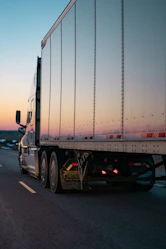 A powerful semi-truck speeding down an open highway under a clear blue sky.