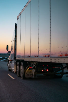 A sleek, modern semi-trailer moving along a highway with a clear blue sky.