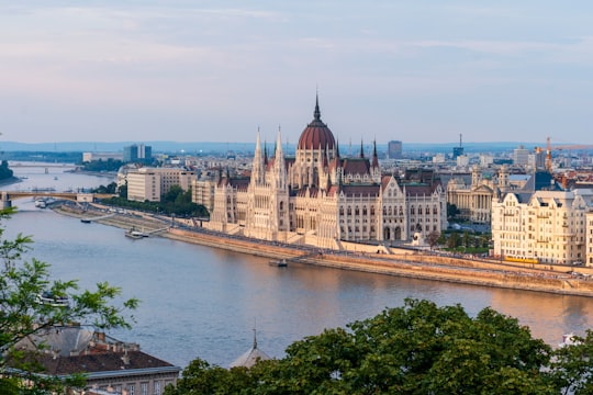 brown concrete building near body of water during daytime in Hungarian Parliament Building Hungary