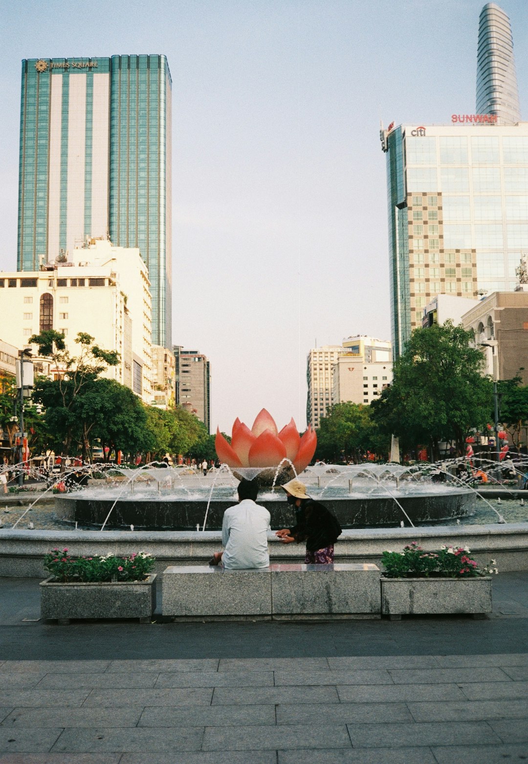 woman in white shirt sitting on gray concrete bench holding red umbrella during daytime