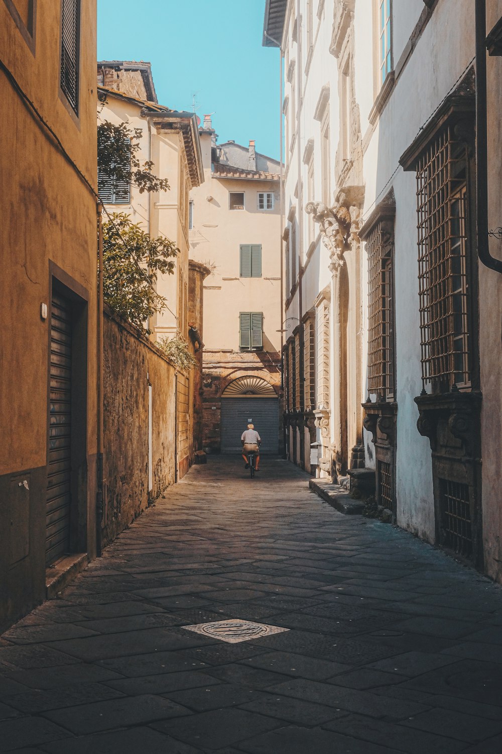 person walking on street between concrete buildings during daytime