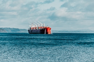 red ship on sea under white clouds during daytime