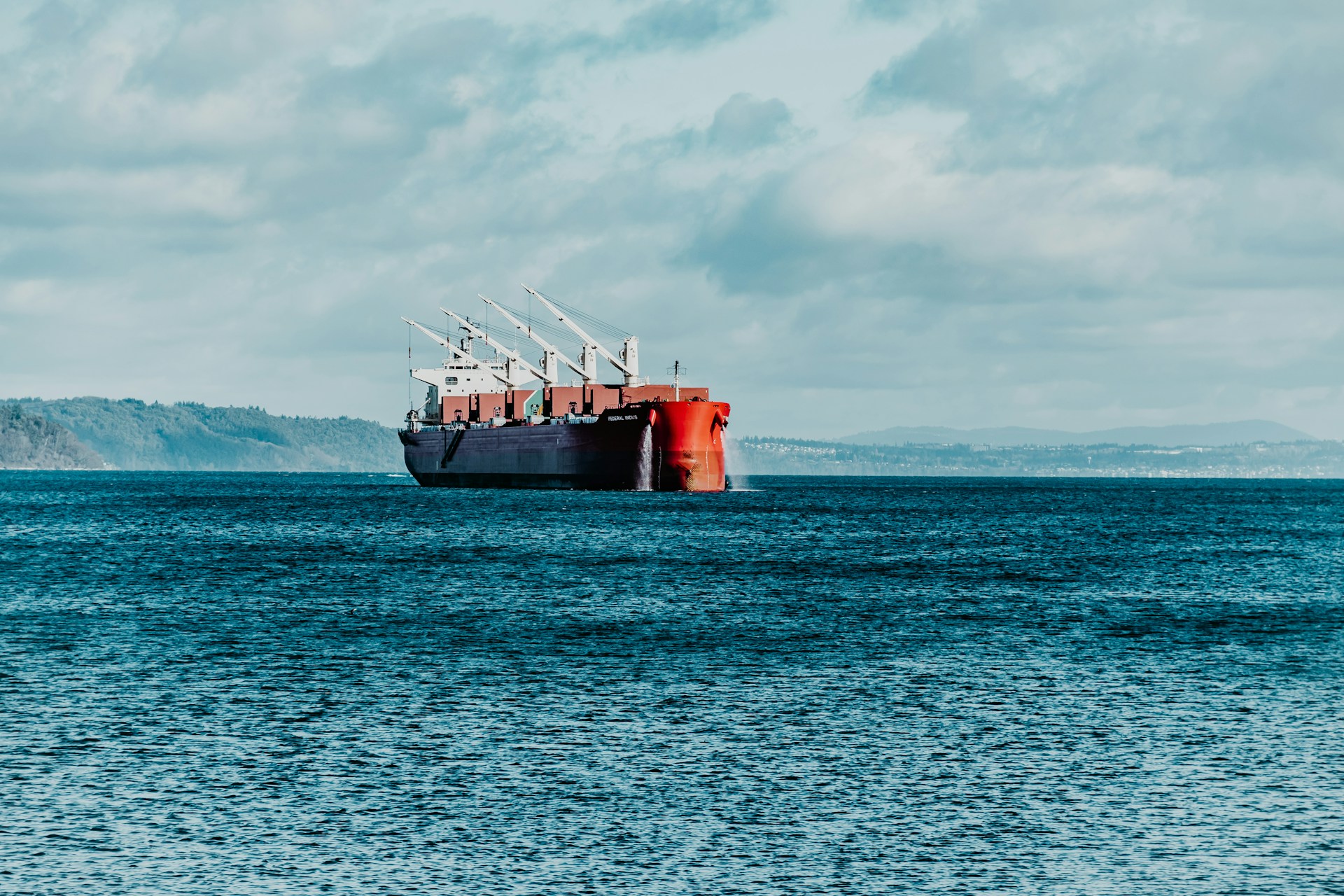 red ship on sea under white clouds during daytime