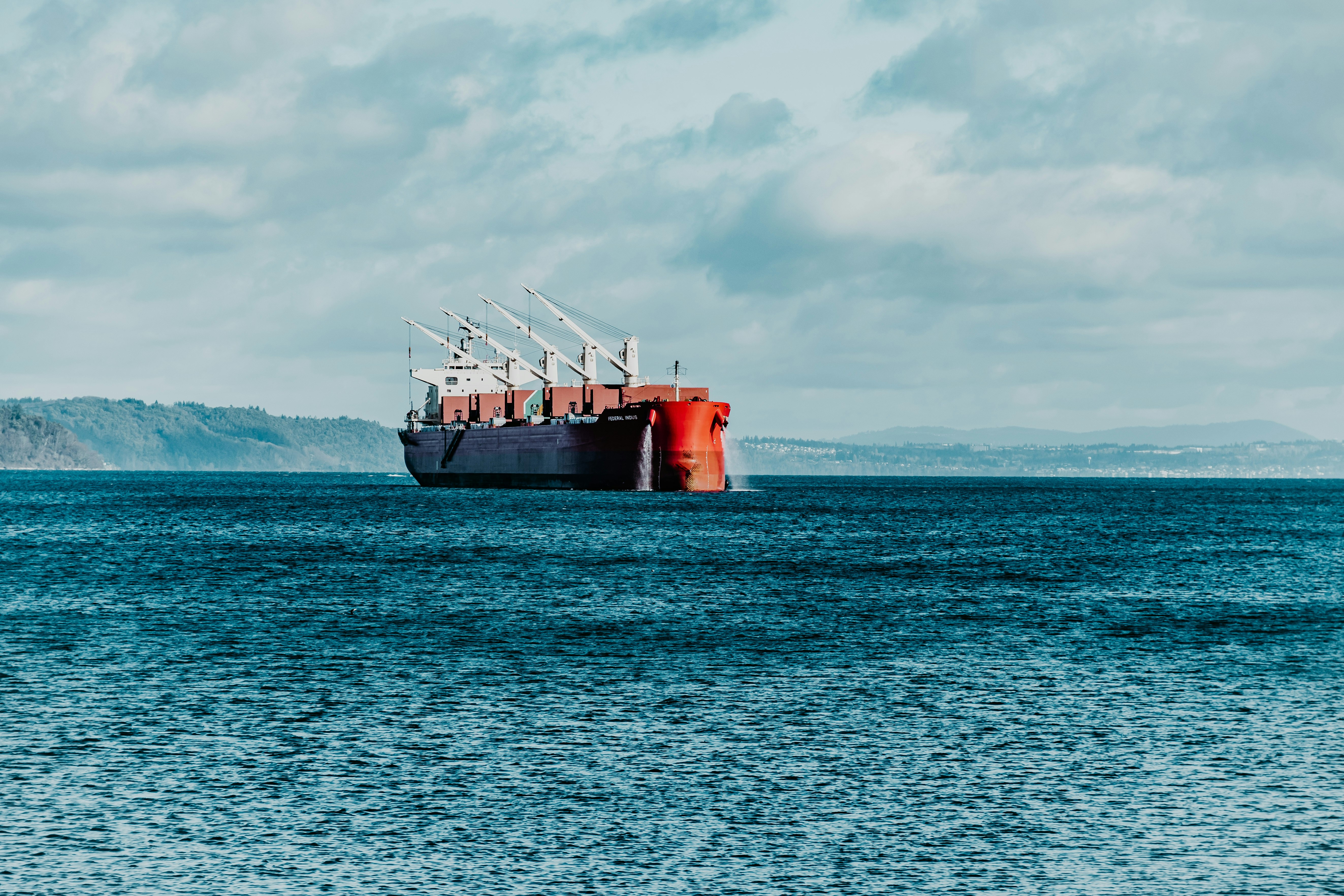 red ship on sea under white clouds during daytime