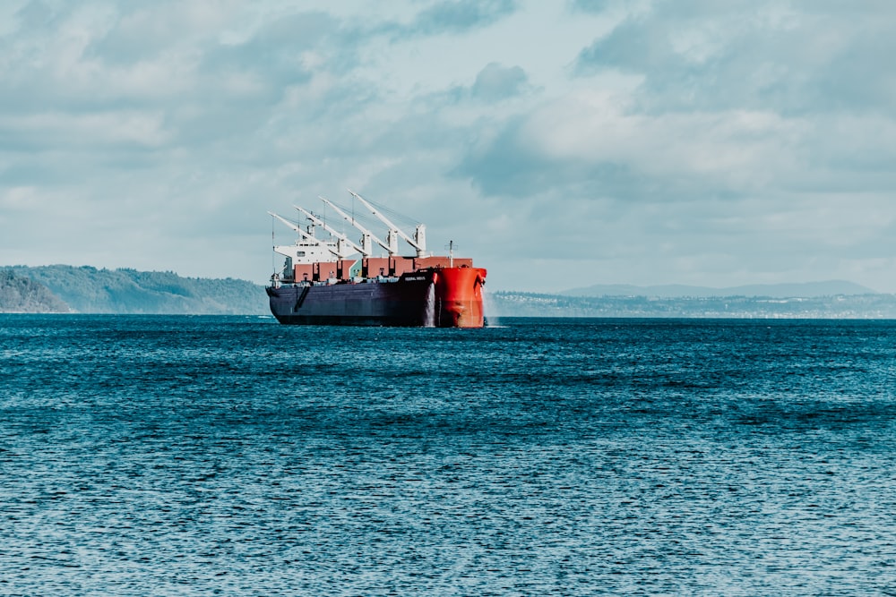navio vermelho no mar sob nuvens brancas durante o dia