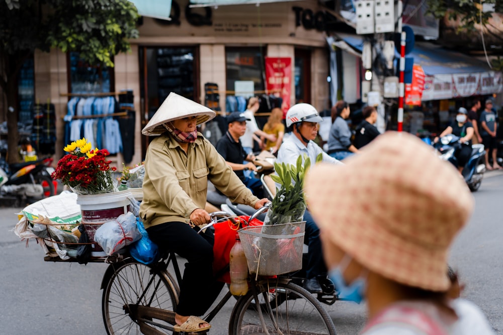 woman in brown jacket and white hat riding on black bicycle during daytime