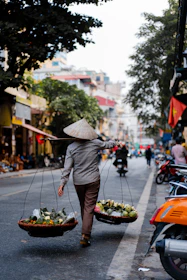 woman in gray coat holding umbrella while walking on street during daytime