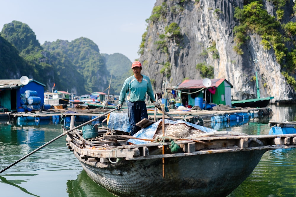 Mann im blauen Hemd steht tagsüber auf dem Boot auf dem Fluss