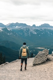 man in gray jacket standing on rock formation during daytime