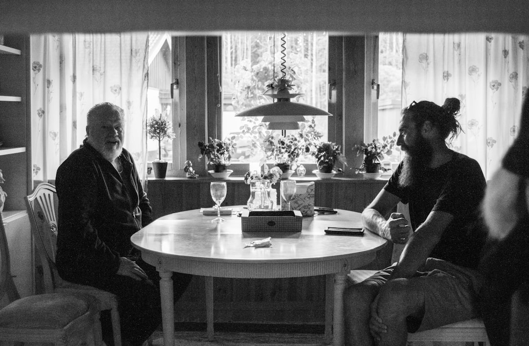 grayscale photo of people sitting on chair in front of table