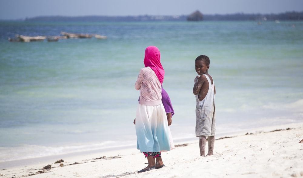 2 women in white and pink dresses standing on beach during daytime