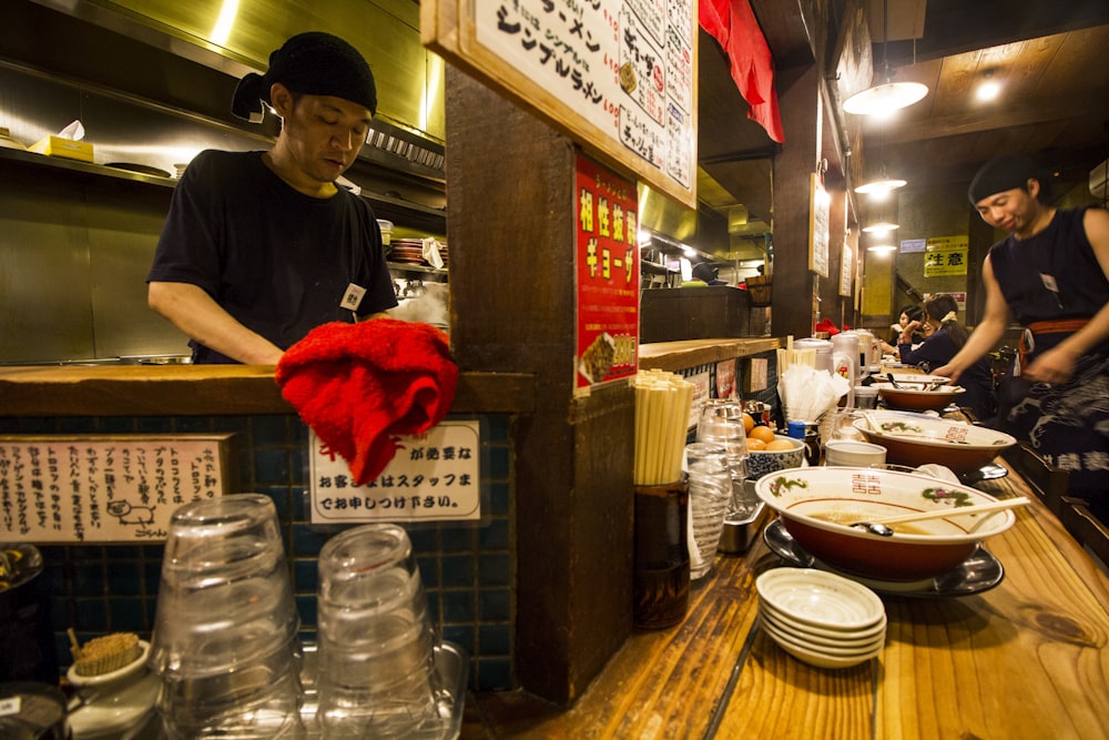 man in white crew neck t-shirt standing beside counter