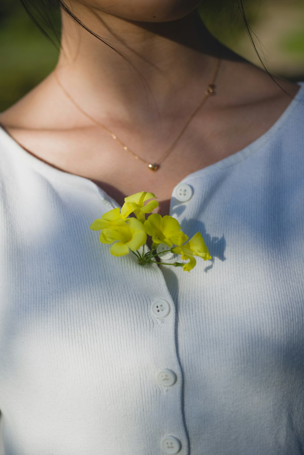 woman in white button up shirt with yellow flower on her neck
