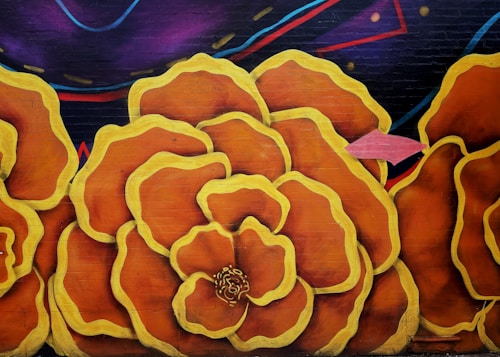 Large, stylized flowers painted on a wall with bold outlines. The flowers are predominantly orange with yellow edges, set against a background of dark purple and blue with abstract designs.