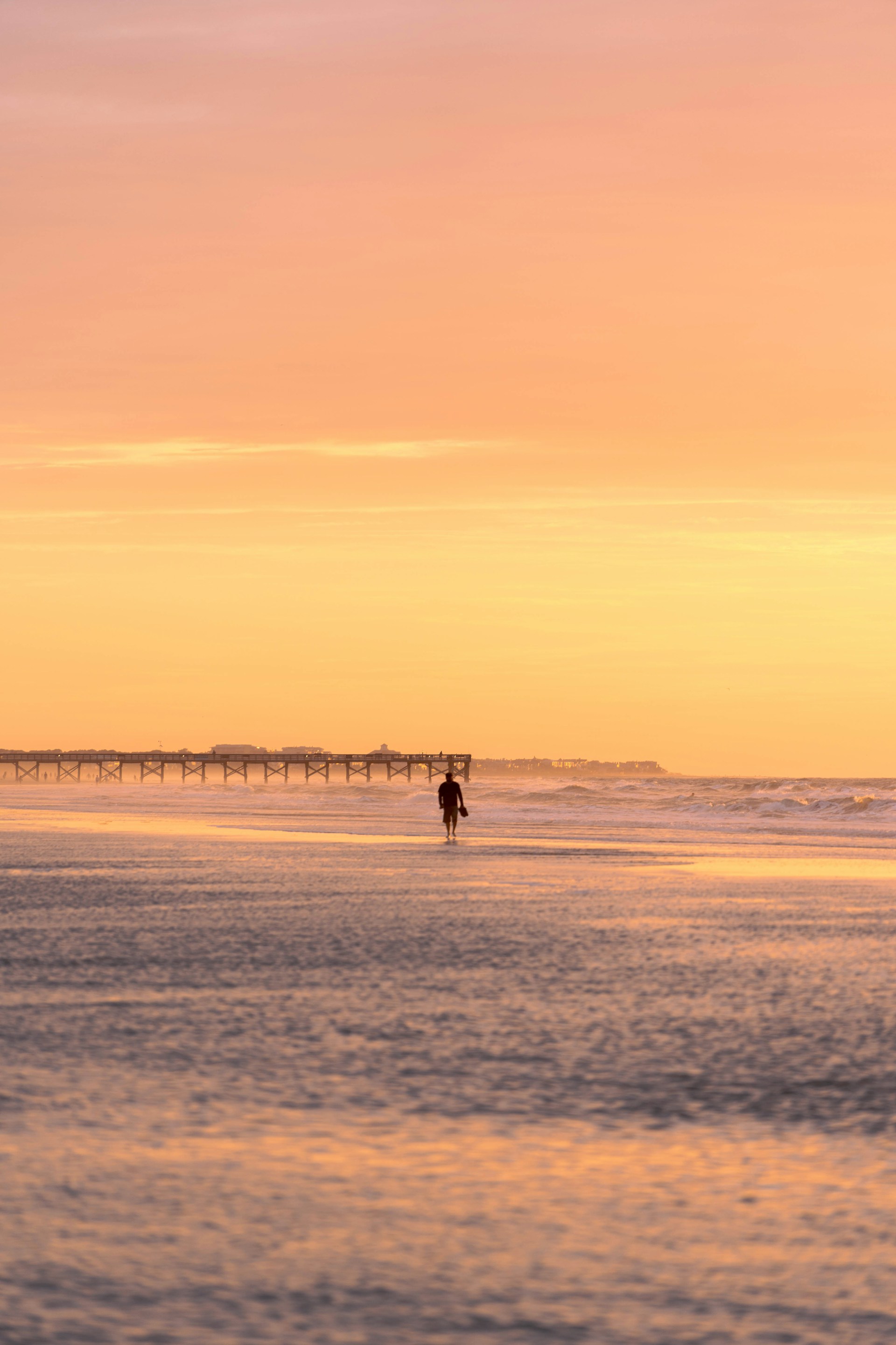 silhouette of 2 people walking on beach during sunset
