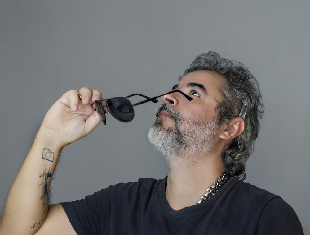 man in black tank top holding black sunglasses