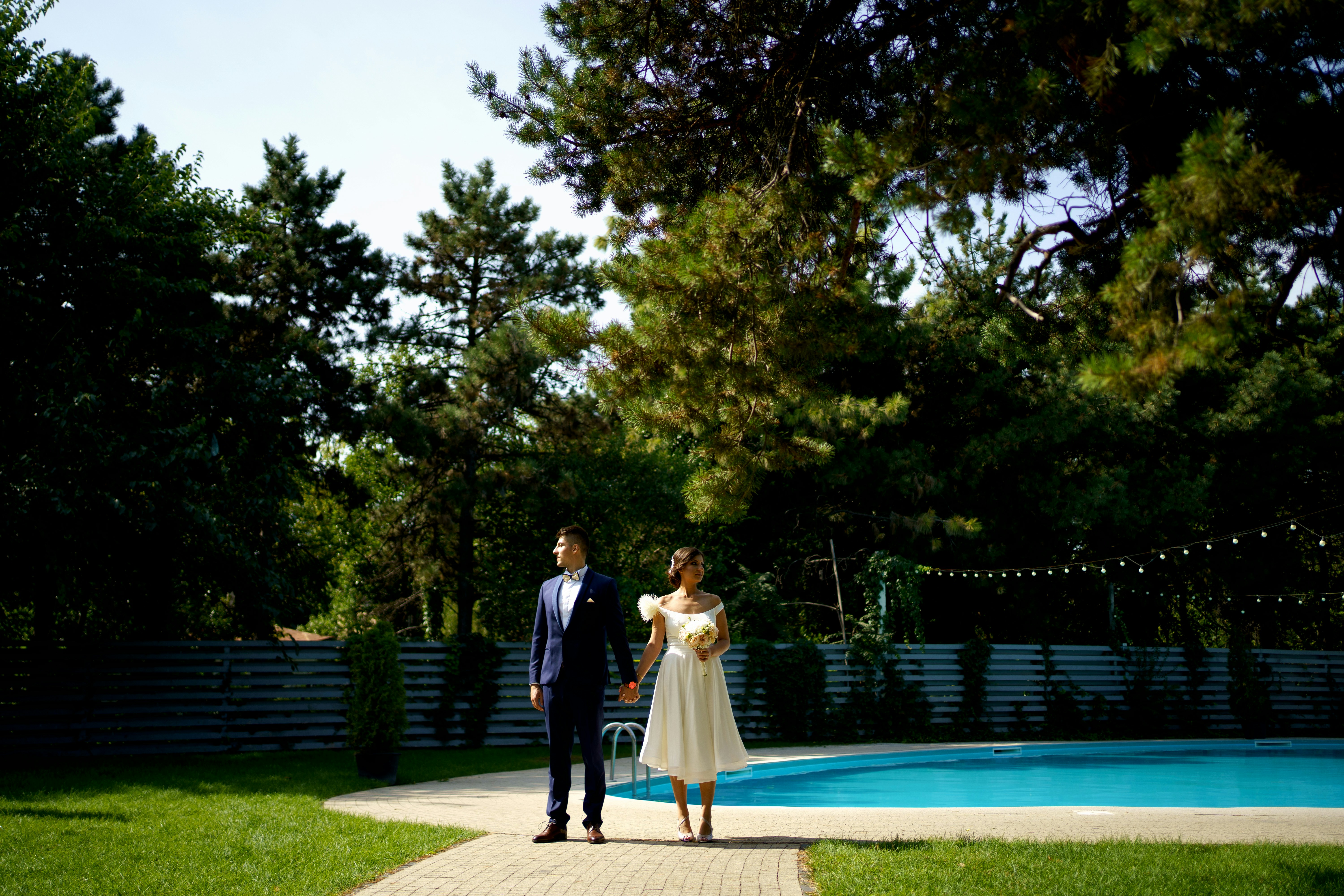 man and woman standing on green grass field near green trees during daytime