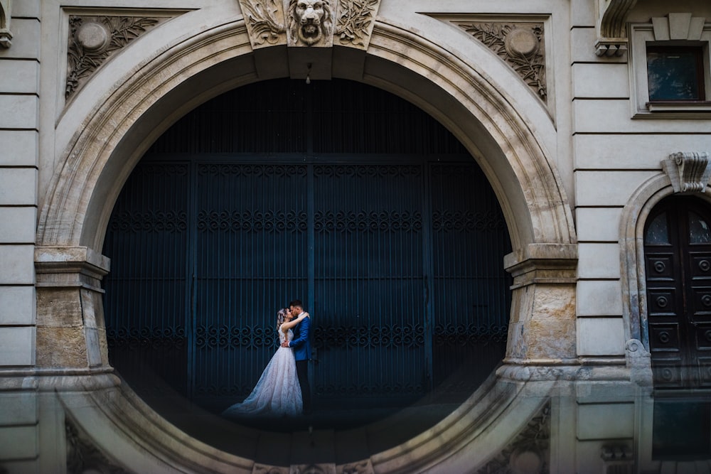 man in blue suit standing in front of blue metal gate