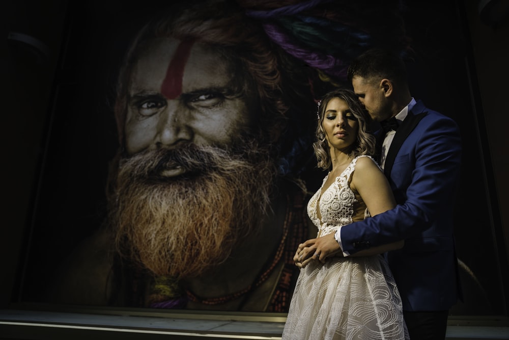 woman in white sleeveless dress beside man in blue suit jacket