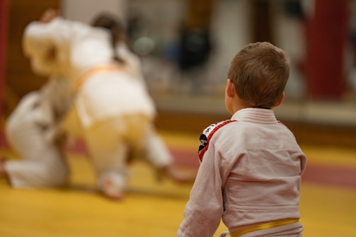 Children and adults practicing mindful movement together during a traditional martial arts workshop in a spacious hall.