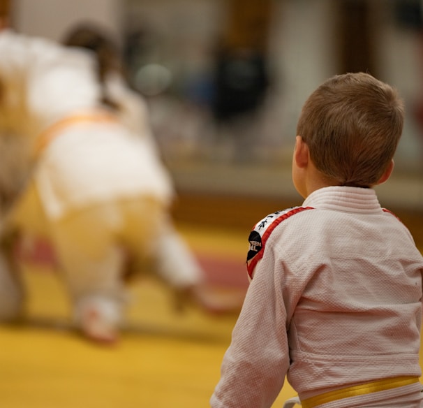 child in pink long sleeve shirt and yellow pants standing on brown wooden floor