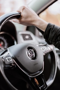 person holding black mercedes benz steering wheel