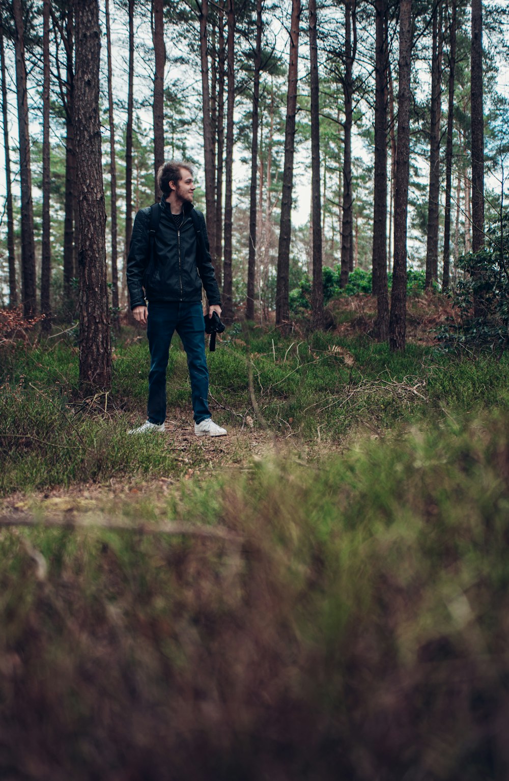 man in black jacket walking on brown grass field