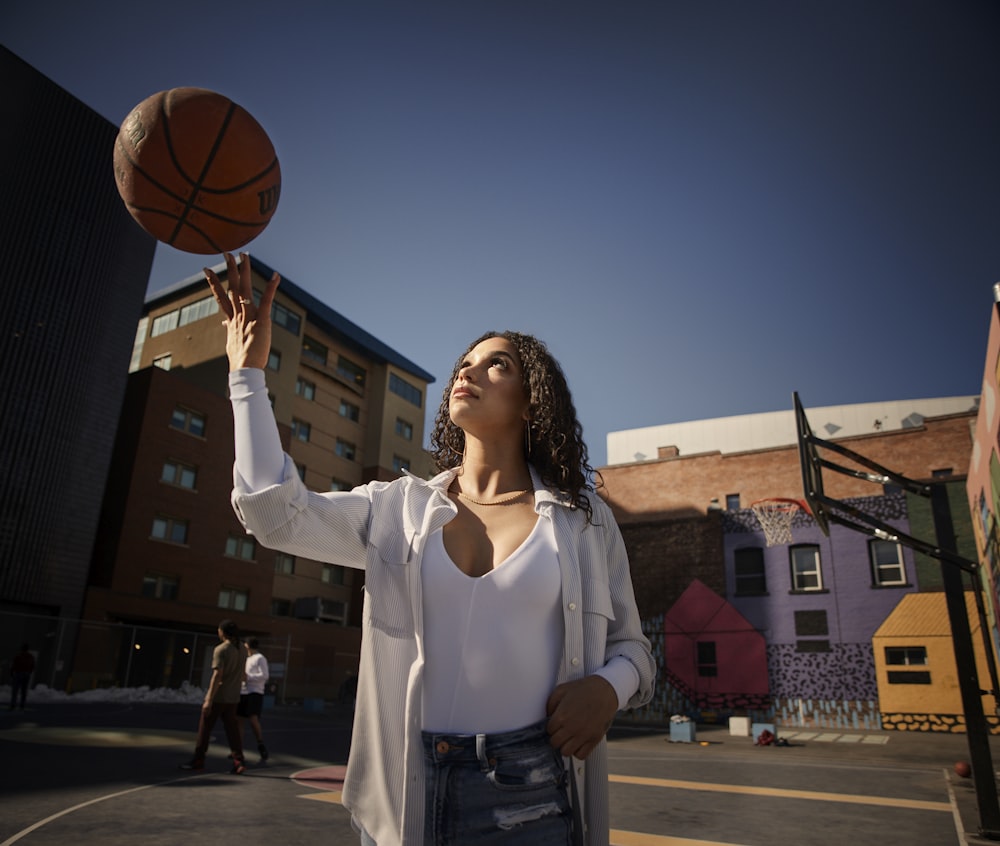 woman in white long sleeve shirt holding basketball