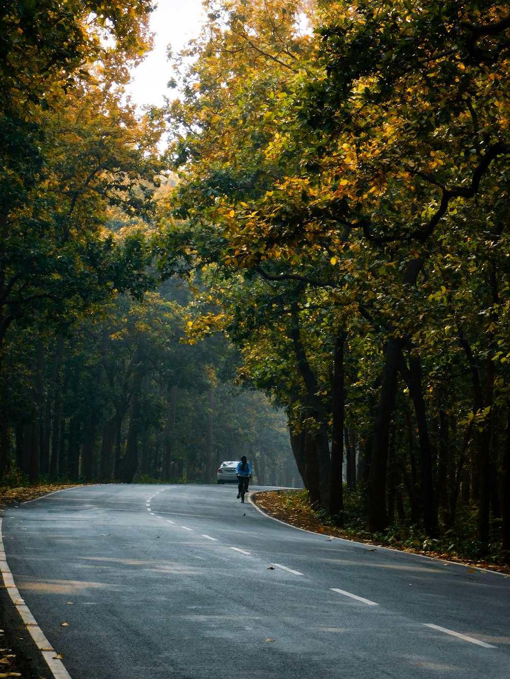 Hombre en chaqueta negra montando motocicleta en carretera de asfalto gris durante el día