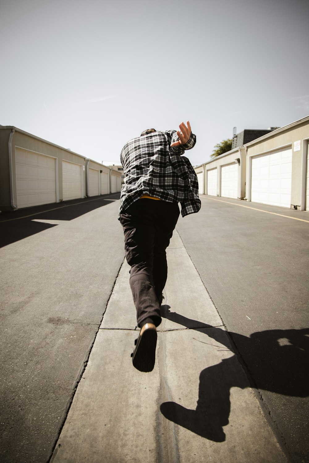 man in black and white plaid dress shirt and black pants standing on gray concrete floor