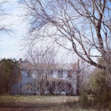 An old, abandoned house with broken windows under a stormy night sky.