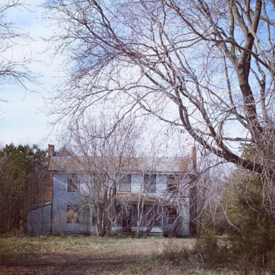 An old, abandoned house with broken windows under a stormy night sky.