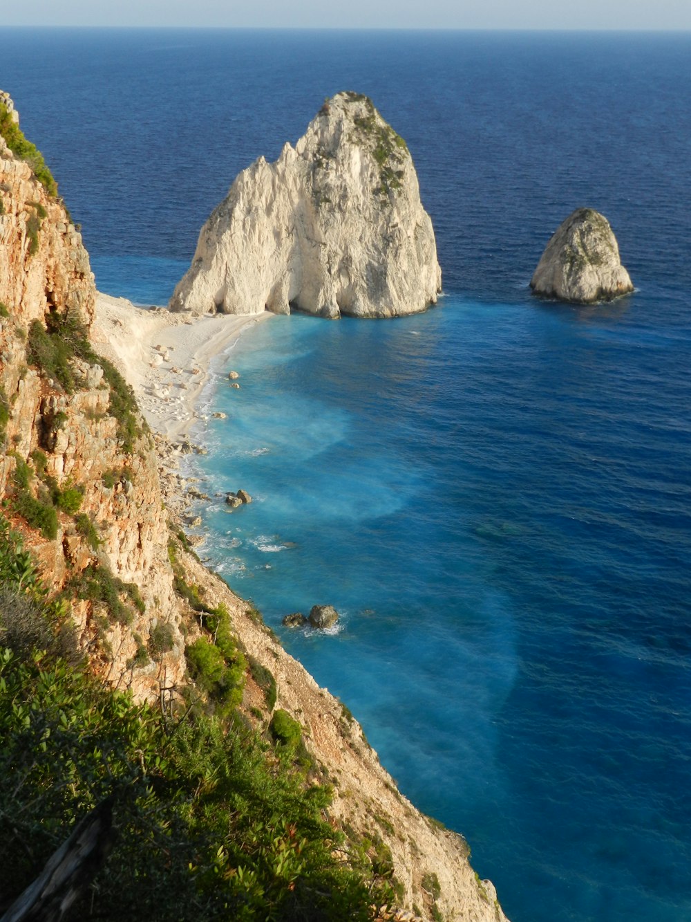 昼間の青い海のそばの茶色の岩山