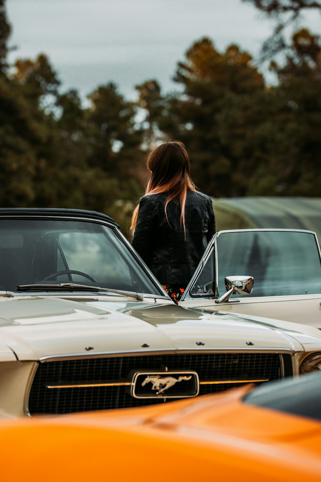 woman in black long sleeve shirt standing beside white car during daytime