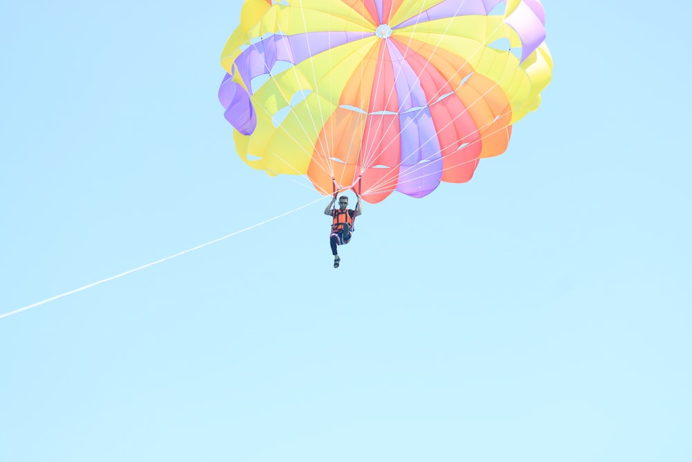 person in black jacket and black pants riding yellow and red parachute