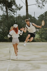 2 women in white and black dress holding tennis racket