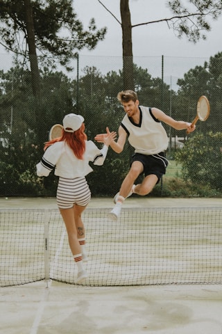 2 women in white and black dress holding tennis racket