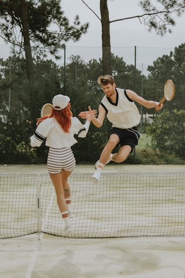2 women in white and black dress holding tennis racket